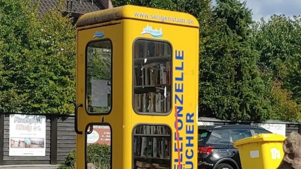 Gelbe ehemalige Telefonzelle mit gefüllten Bücherregalen am Trieler Ring.