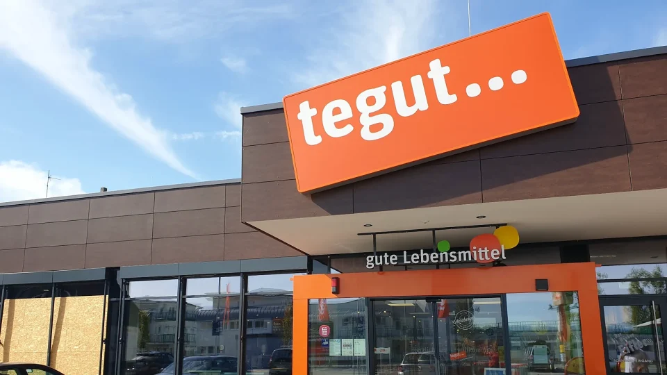 Eingang des tegut-Marktes in der Steinheimer Straße mit orangefarbenem tegut-Logo über der Glasfront.