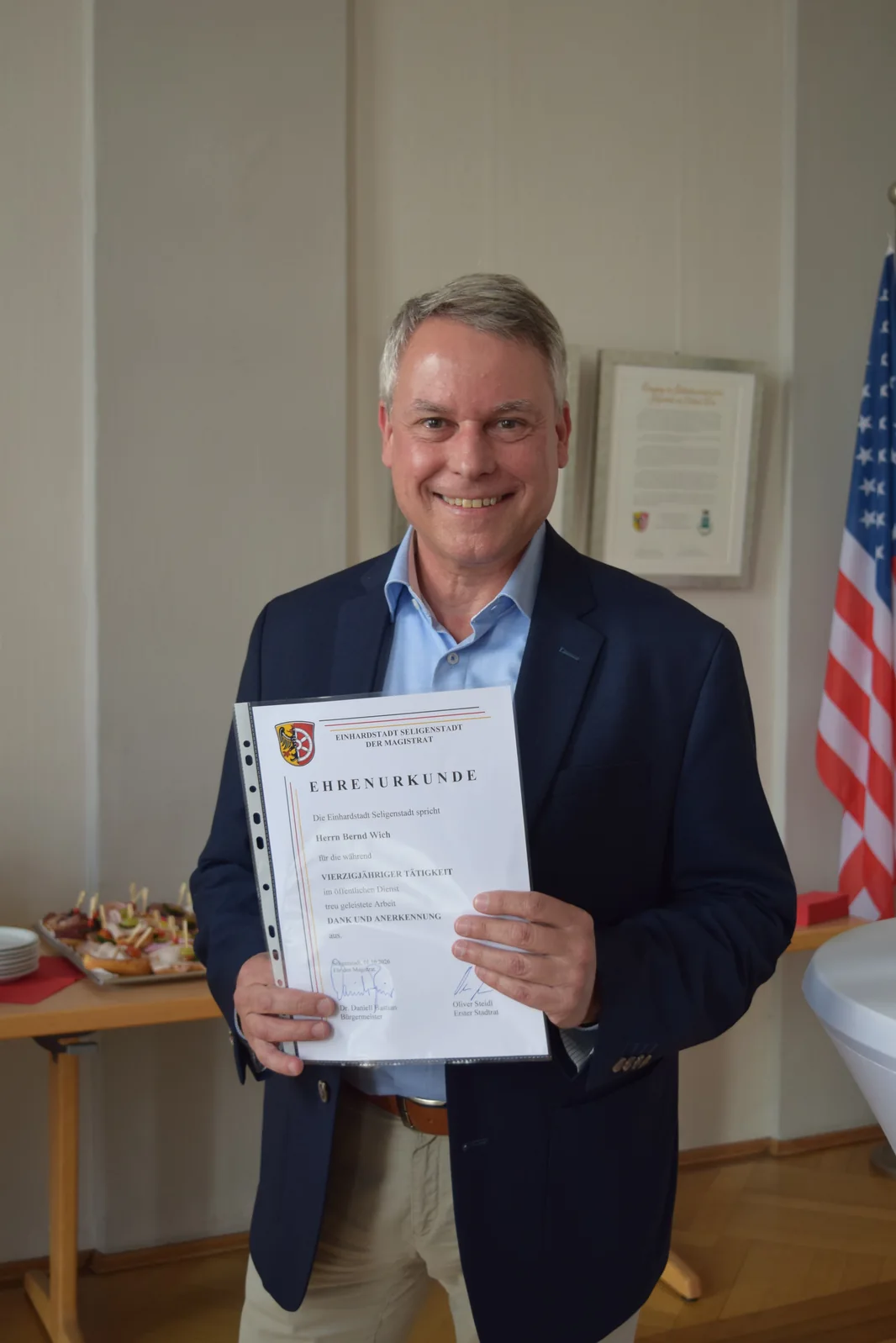Bernd Wich hält die Ehrenurkunde für seine vierzigjährige Tätigkeit im öffentlichen Dienst.