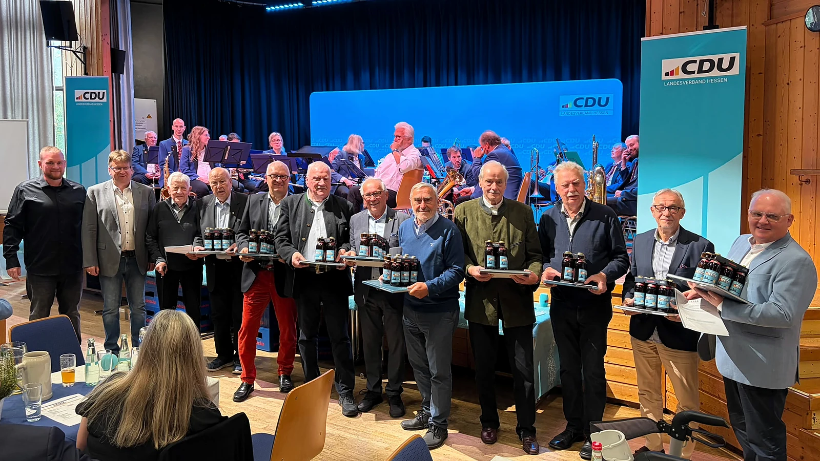Eine Gruppe steht vor der Bühne im Bürgerhaus und hält Urkunden und Bierpräsente.
